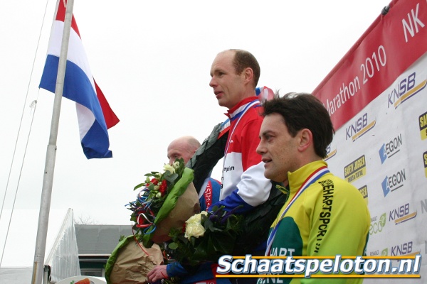 De nieuwe Nederlands Kampioen bij de Masters, Kurt van de Nes, luistert samen met Arnold Stam en Paul Robijn naar het Wilhelmus bij de huldiging van het NK op kunstijs.